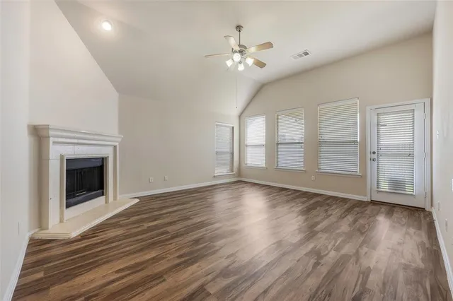 a view of an empty room with wooden floor fireplace and a window