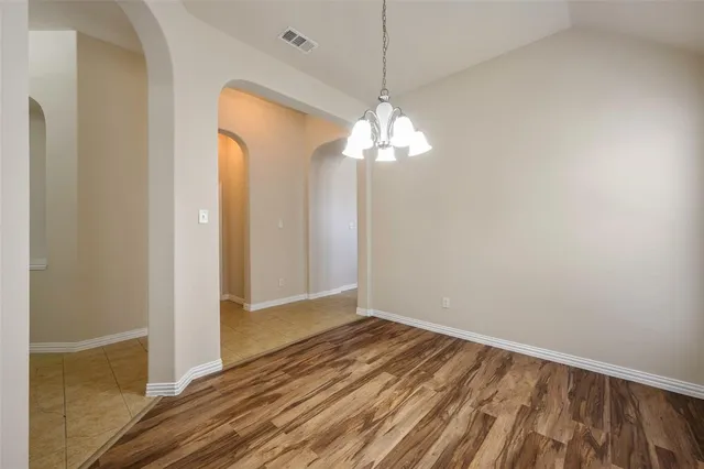 an empty room with wooden floor chandelier and closet
