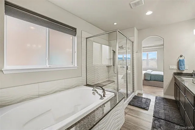a bathroom with a tub a sink and a large mirror