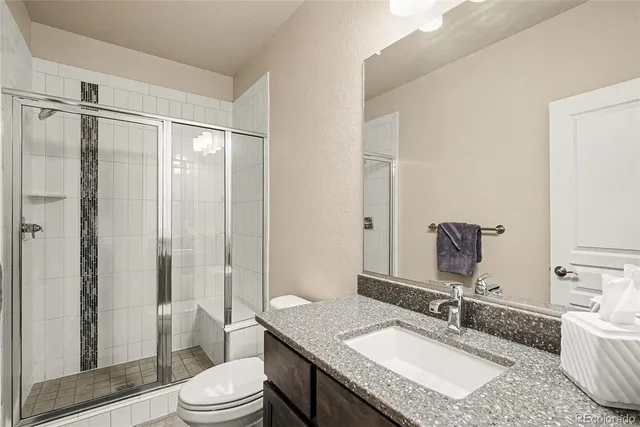 a bathroom with a granite countertop sink toilet a mirror a vanity and shower