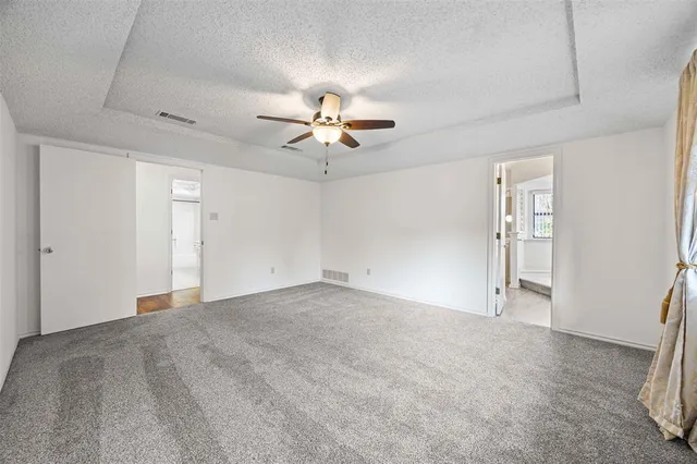 an empty room with chandelier fan and windows