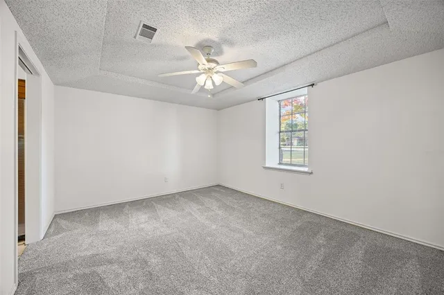 an empty room with chandelier fan and windows
