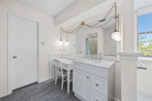 a bathroom with a granite countertop sink a mirror and a wooden floor