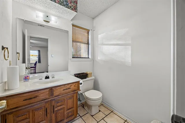 a bathroom with a granite countertop toilet a sink a mirror and a window