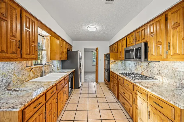 a large kitchen with stainless steel appliances granite countertop a sink and cabinets