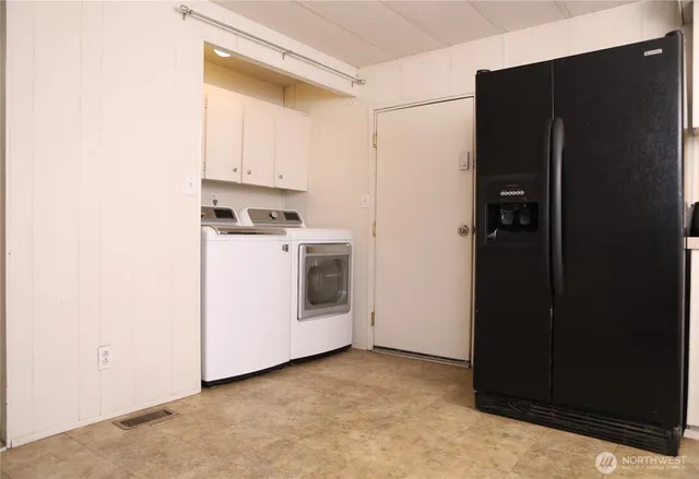 a view of a refrigerator in kitchen and white cabinets