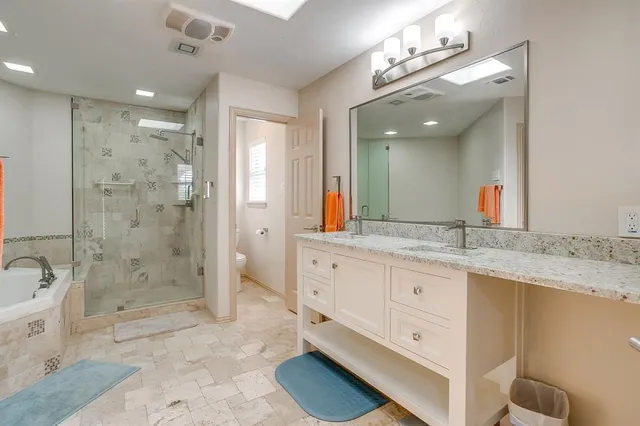 a bathroom with a granite countertop double vanity sink a mirror and a shower