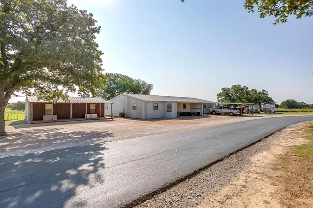 a front view of a house with a yard and a large tree