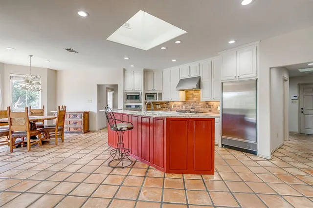 a kitchen with stainless steel appliances granite countertop a refrigerator oven a sink a dining table and chairs