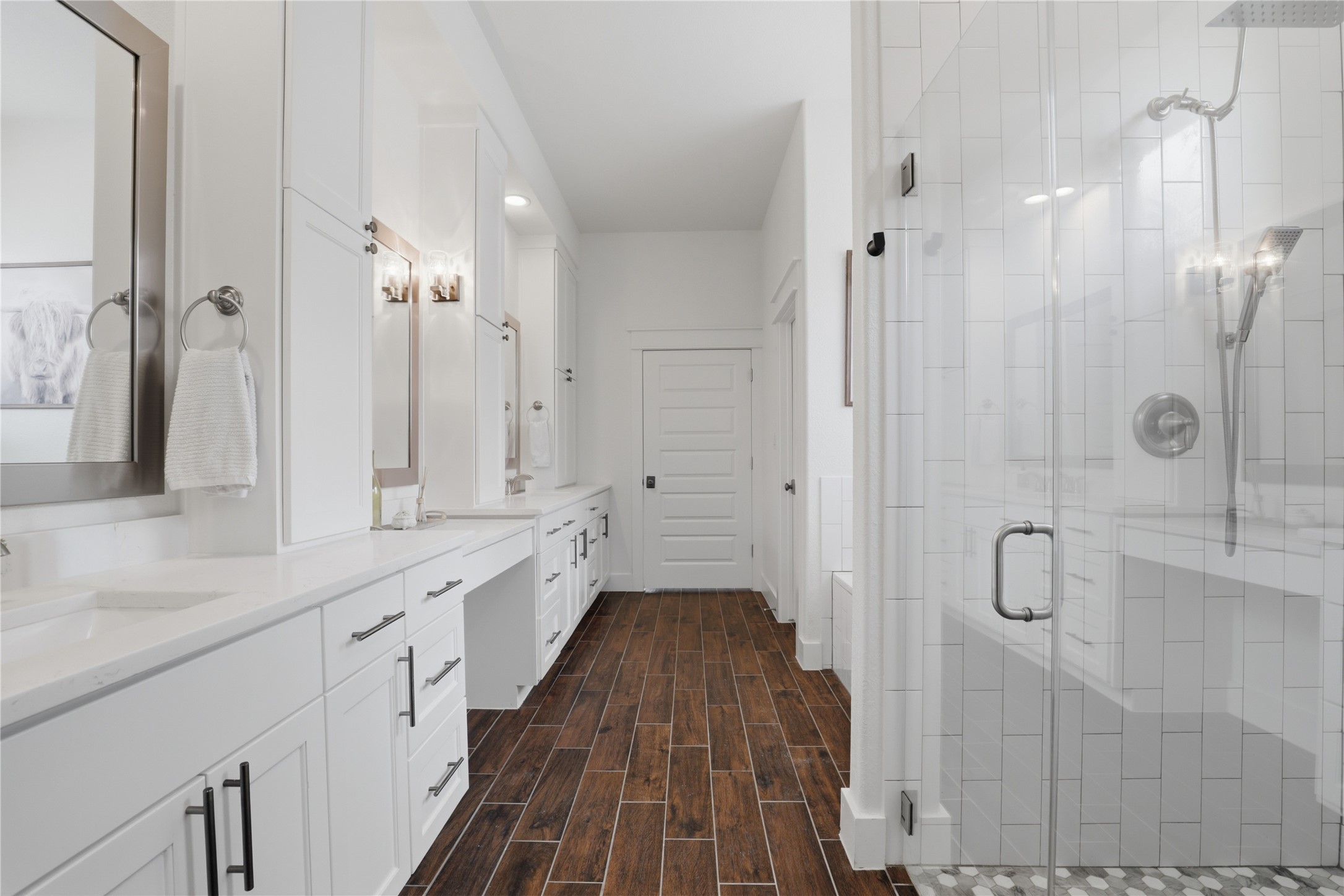 133 Greg Lane Jarrell, TX 76537 - Photo 15 of 24 Spacious bathroom featuring wood-finish flooring, an enclosed shower with subway tile, dual vanities with white countertops, and white cabinetry with brushed nickel hardware