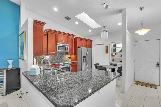a kitchen with stainless steel appliances granite countertop a sink refrigerator and cabinets