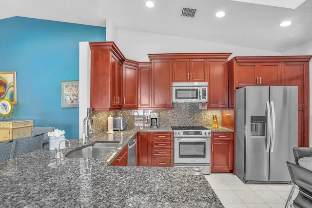 a kitchen with stainless steel appliances granite countertop a refrigerator sink and stove