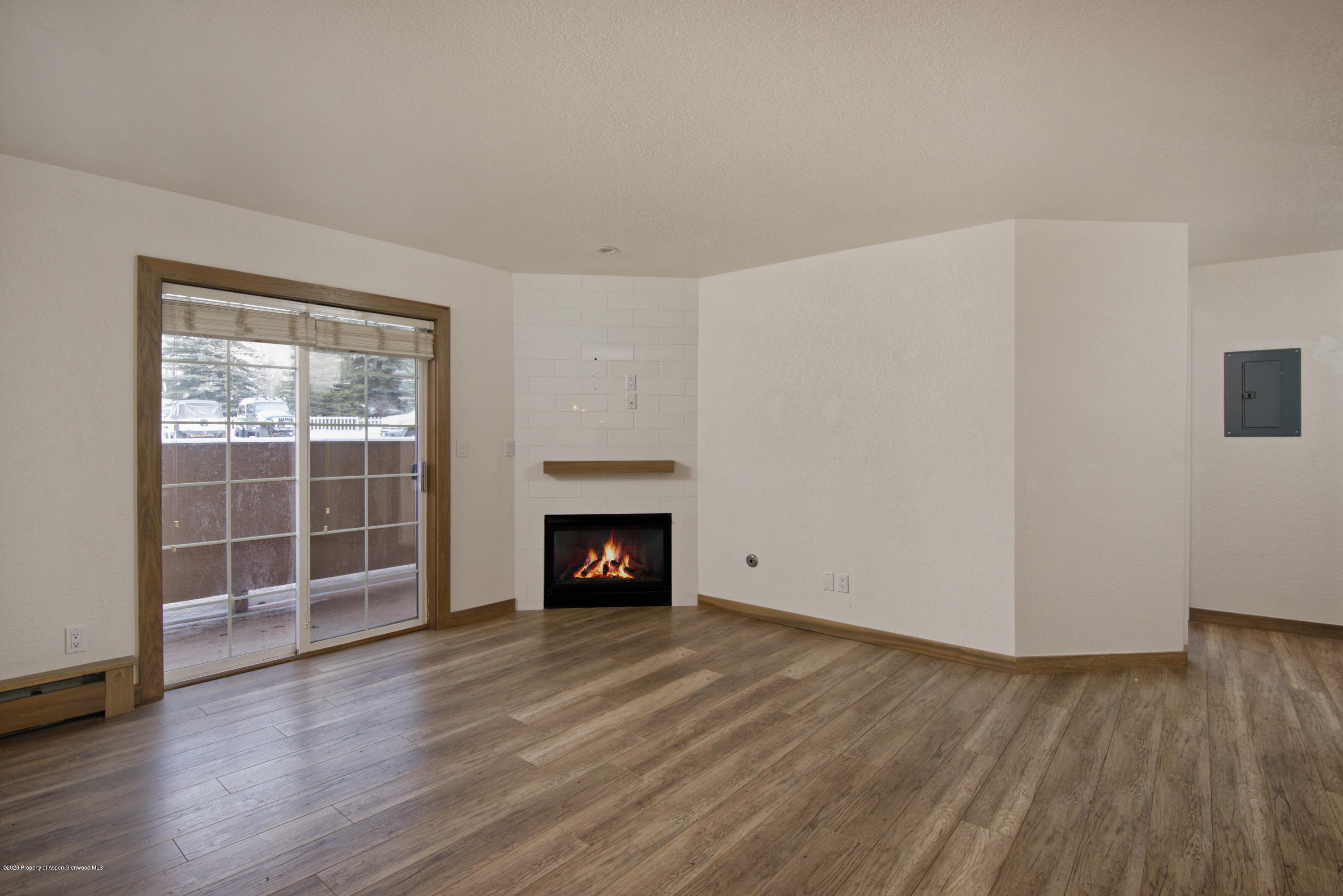 an empty room with wooden floor a fireplace and windows