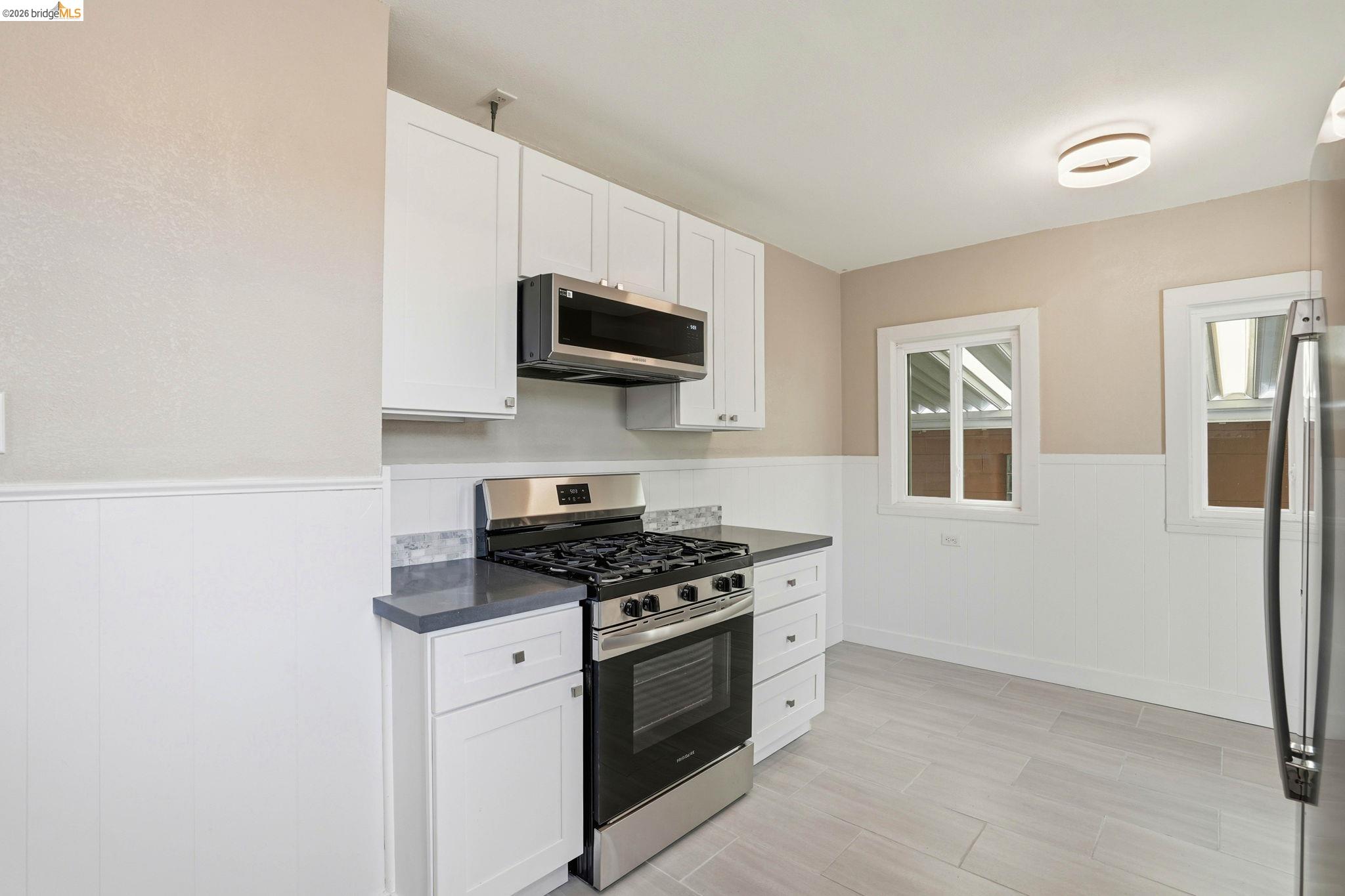 840 Key Rte Boulevard Albany, CA 94706 - Photo 15 of 43 Kitchen featuring a wainscoted wall, stainless steel appliances, and white cabinets