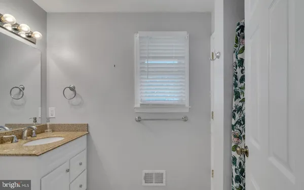 a bathroom with a granite countertop sink and a mirror