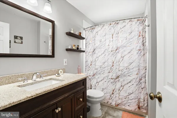 a bathroom with a granite countertop sink a toilet and a mirror