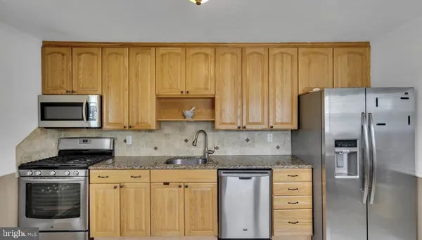 a kitchen with granite countertop a stove a sink stainless steel appliances and cabinets