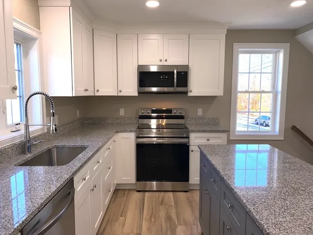 a kitchen with granite countertop a stove a sink and a microwave