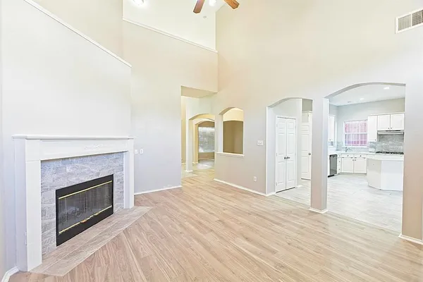 an empty room with wooden floor fireplace and windows