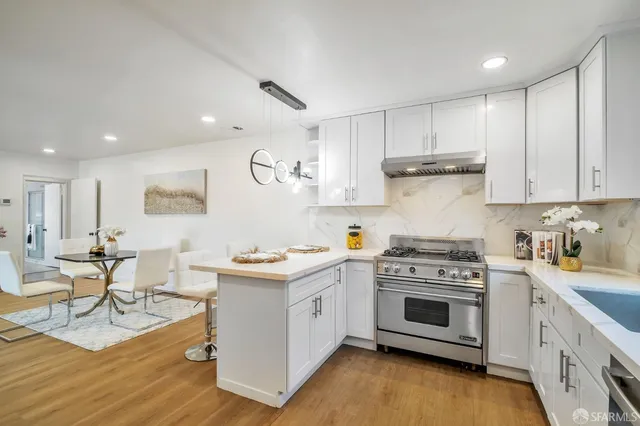 a kitchen with a stove a sink and white cabinets