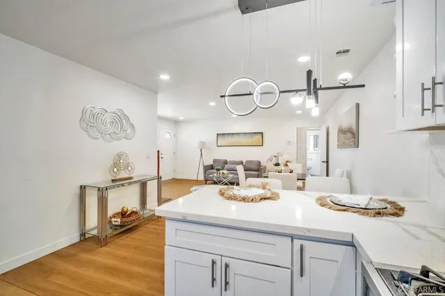 a kitchen with a sink dishwasher a dining table and chairs with wooden floor