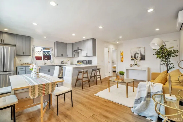 a kitchen with stainless steel appliances kitchen island granite countertop a dining table chairs refrigerator and sink