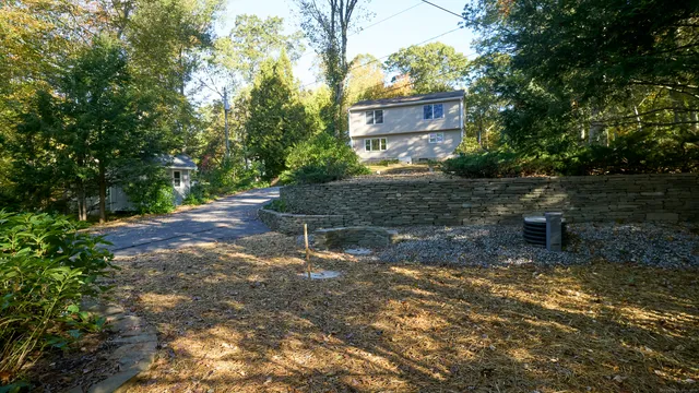 a view of a tall white house with a clock and a yard