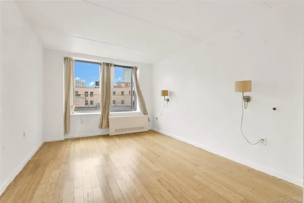 a view of an empty room with a window and wooden floor