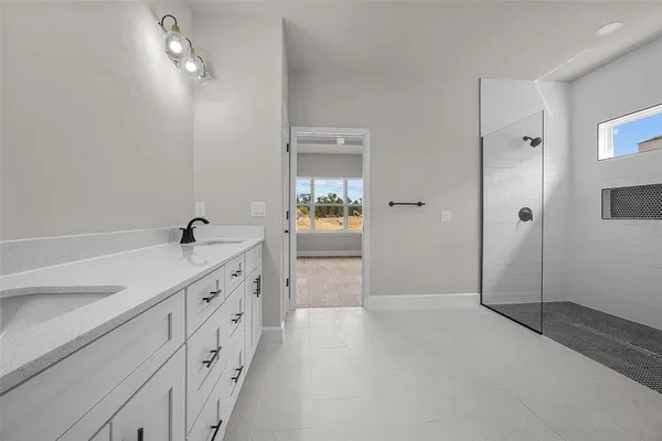 a bathroom with a double vanity sink a toilet and shower