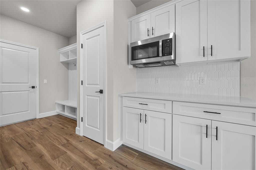 6694 Southwest 11th Lane Gainesville, FL 32607 - Photo 15 of 27 a view of a kitchen with white cabinets stainless steel appliances and wooden floor