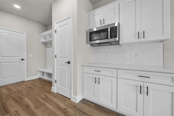 a view of a kitchen with white cabinets stainless steel appliances and wooden floor