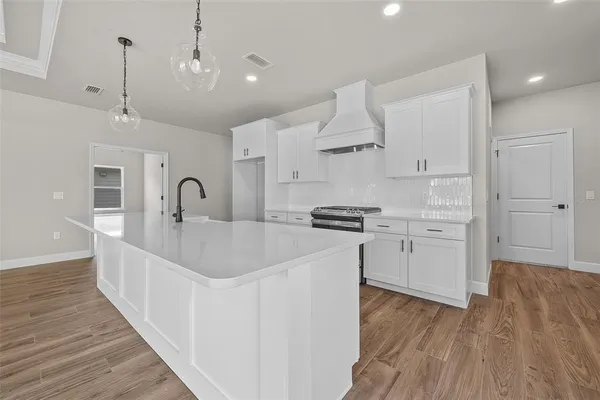 a kitchen with white cabinets a sink and wooden floor