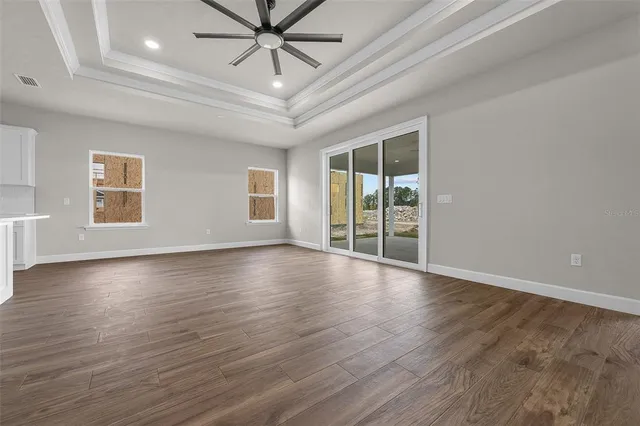an empty room with wooden floor fan and windows