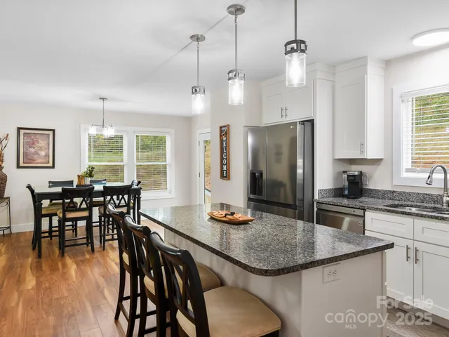 a kitchen with stainless steel appliances granite countertop a dining table chairs stove refrigerator and wooden floor