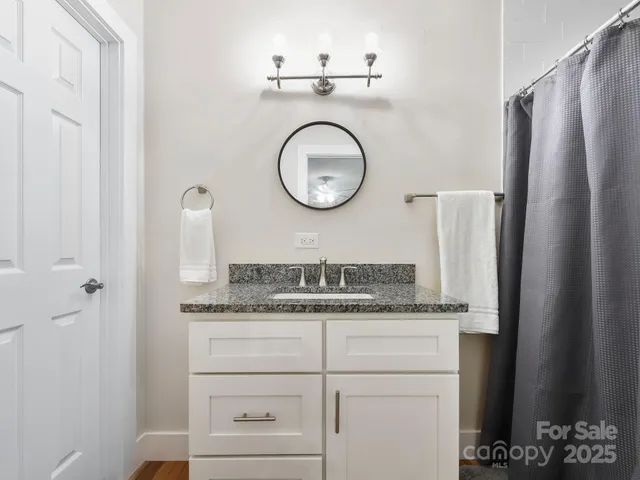 a bathroom with a granite countertop sink a mirror and shower