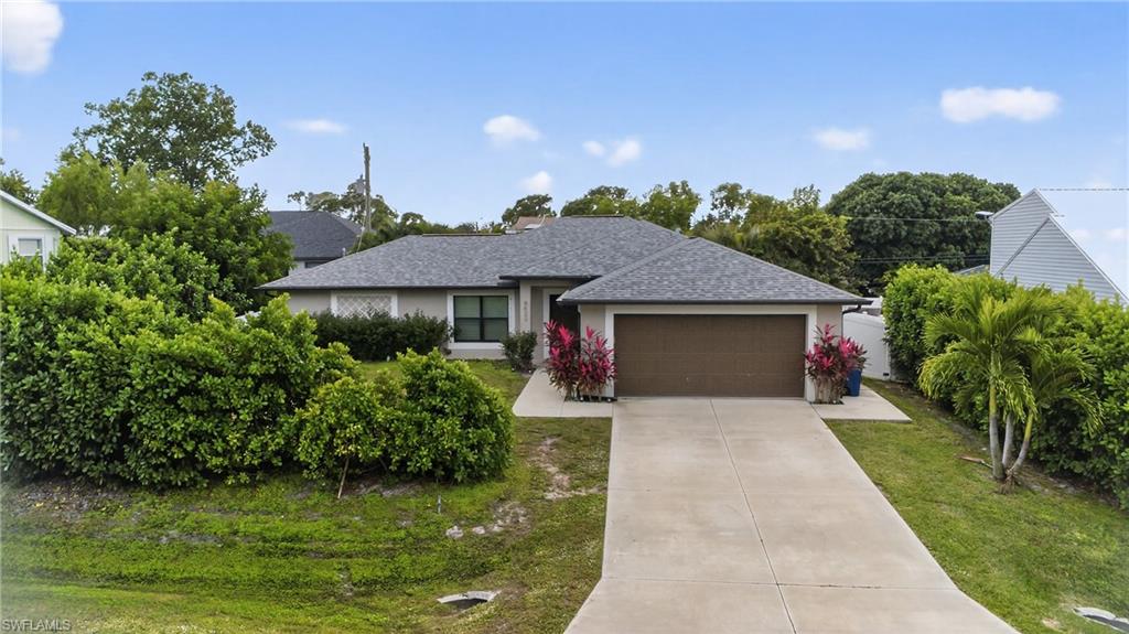 8422 Cardinal Road Fort Myers, FL 33967 - Photo 1 of 24 Single story home with a shingled roof, concrete driveway, a garage, a chimney, and stucco siding