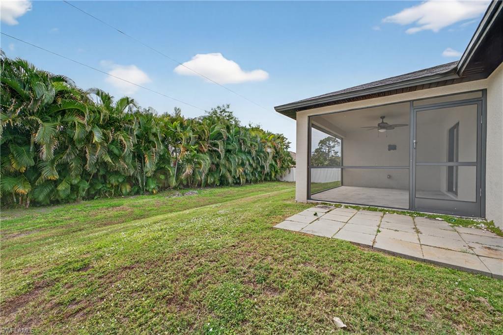 8422 Cardinal Road Fort Myers, FL 33967 - Photo 24 of 24 View of grassy yard featuring ceiling fan, a sunroom, and a patio area