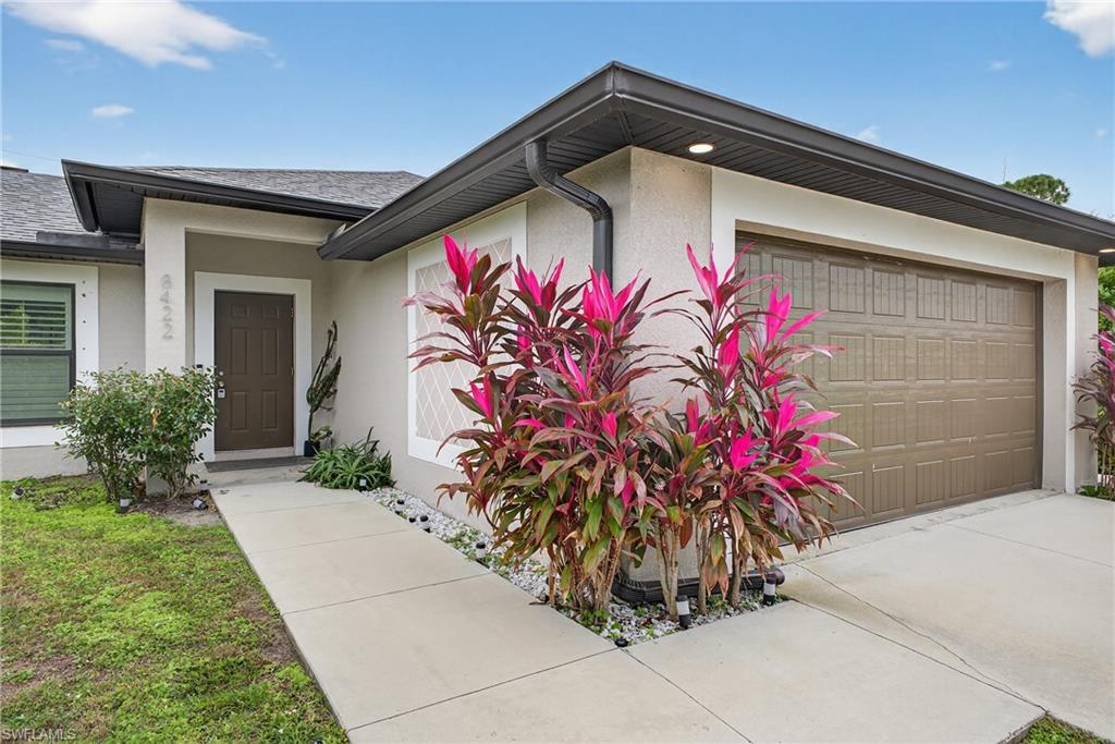 8422 Cardinal Road Fort Myers, FL 33967 - Photo 3 of 24 Entrance to property with stucco siding, a shingled roof, and a garage