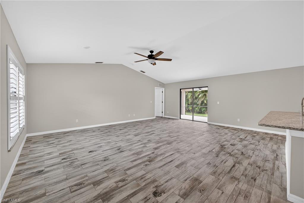 8422 Cardinal Road Fort Myers, FL 33967 - Photo 4 of 24 Unfurnished living room featuring light wood-style floors, vaulted ceiling, and a ceiling fan