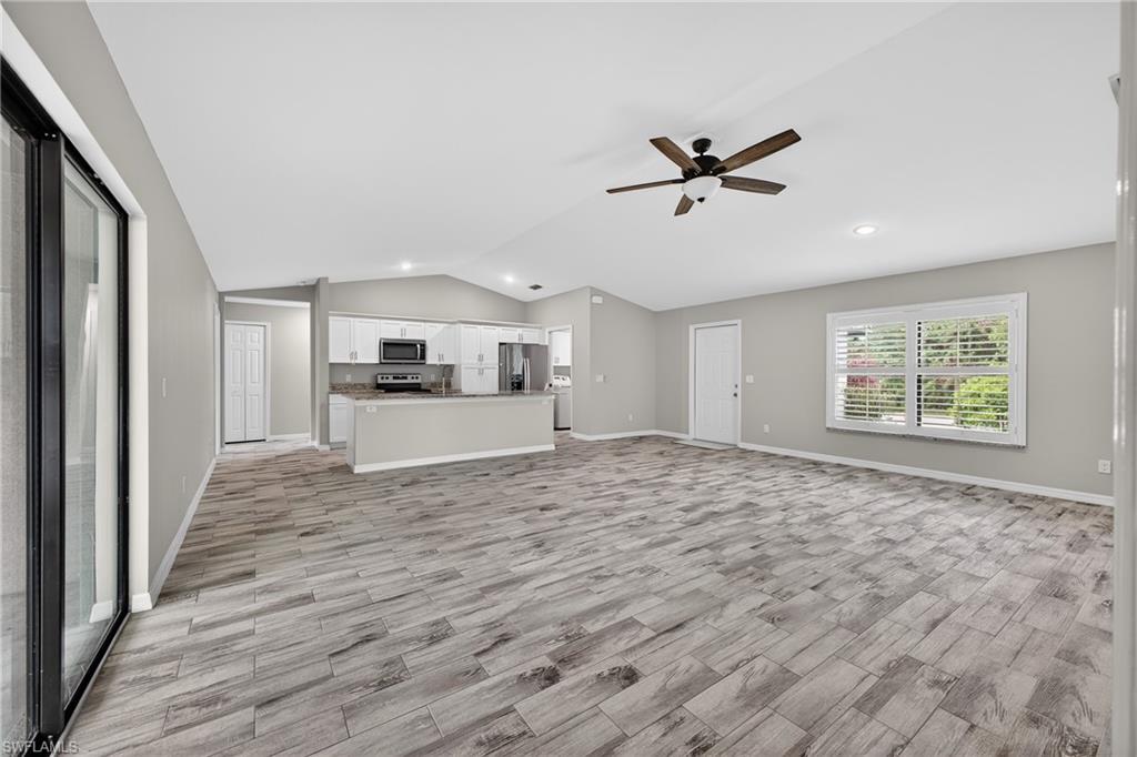 8422 Cardinal Road Fort Myers, FL 33967 - Photo 8 of 24 Unfurnished living room featuring vaulted ceiling, wood finish floors, a ceiling fan, recessed lighting, and washer / dryer