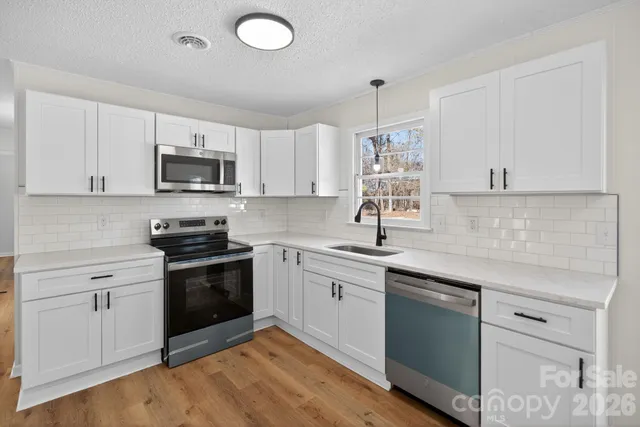 a kitchen with granite countertop a sink cabinets and stainless steel appliances