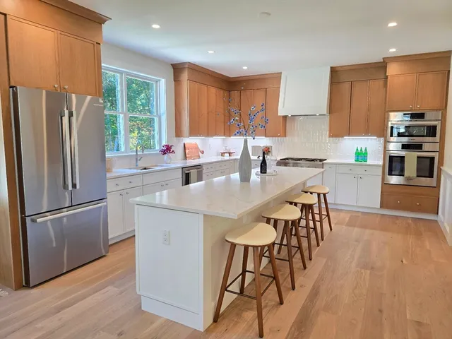 a kitchen with stainless steel appliances a dining table chairs refrigerator and microwave