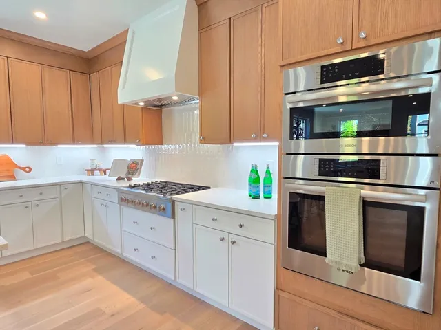 a kitchen with stainless steel appliances white cabinets and a stove top oven