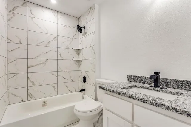 a bathroom with a granite countertop sink a toilet a mirror a bathtub and shower