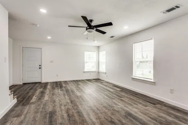 a view of empty room with wooden floor and fan