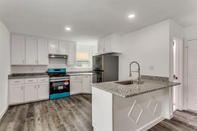 a kitchen with stainless steel appliances granite countertop a sink stove refrigerator and white cabinets