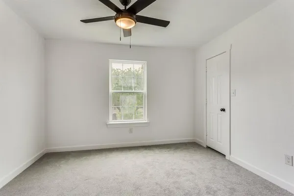 an empty room with a window and a fan