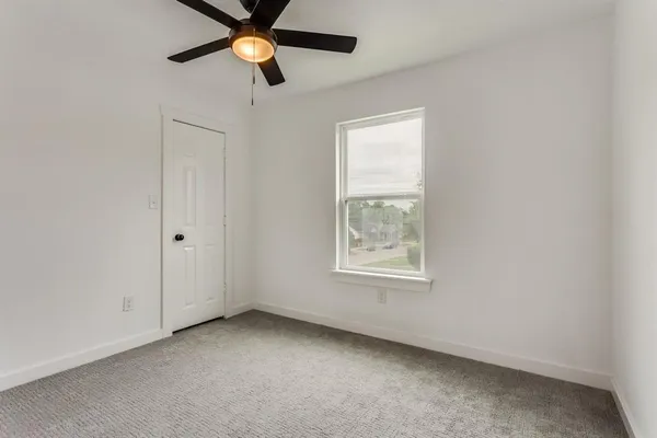an empty room with windows and a ceiling fan