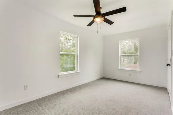 an empty room with a window and a fan