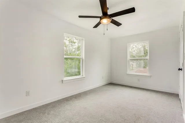 an empty room with a window and a fan